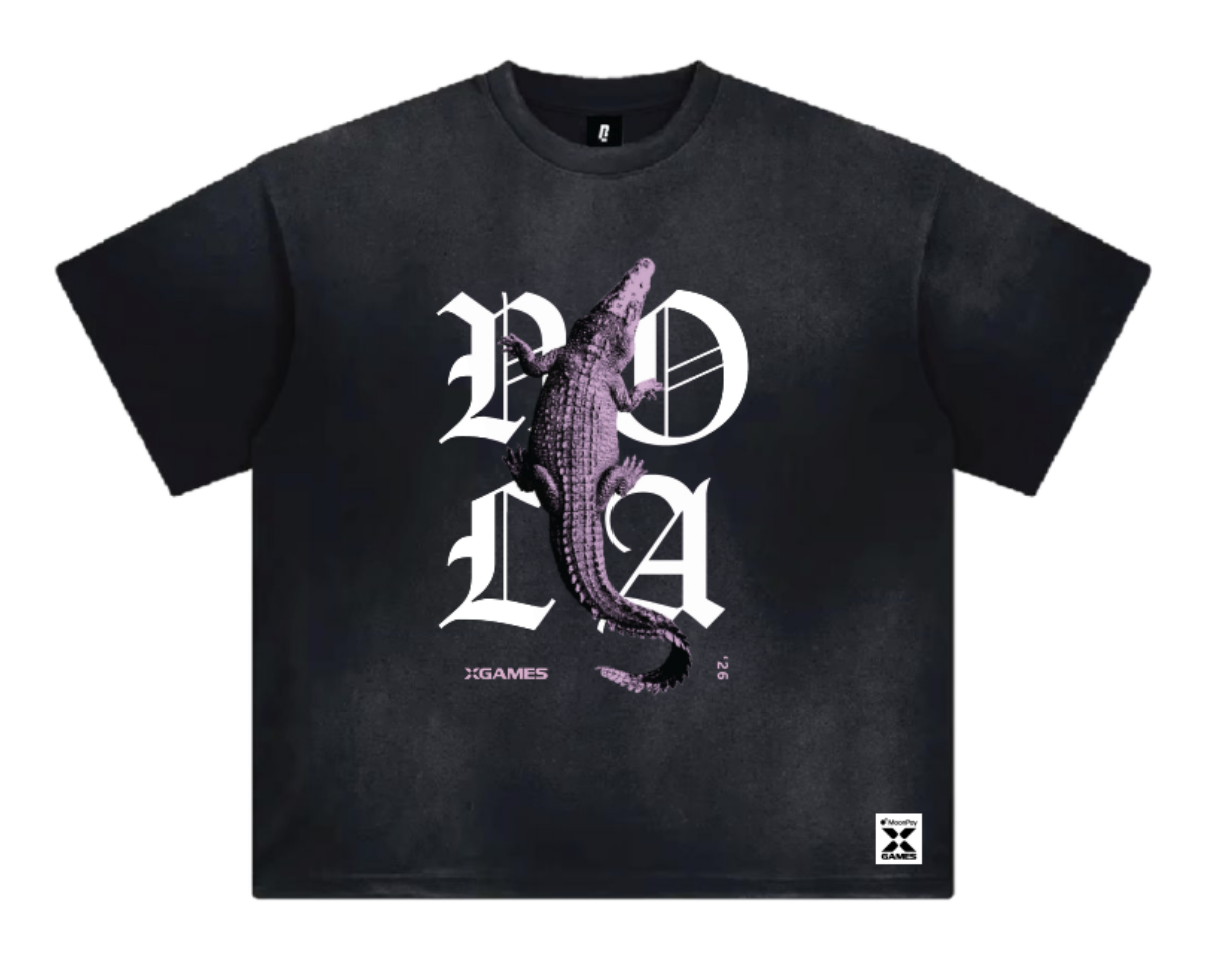 A black short-sleeve t-shirt with a graphic print featuring a crocodile over the letters 'NOLA' in white gothic font, with 'XGAMES '26' printed below.